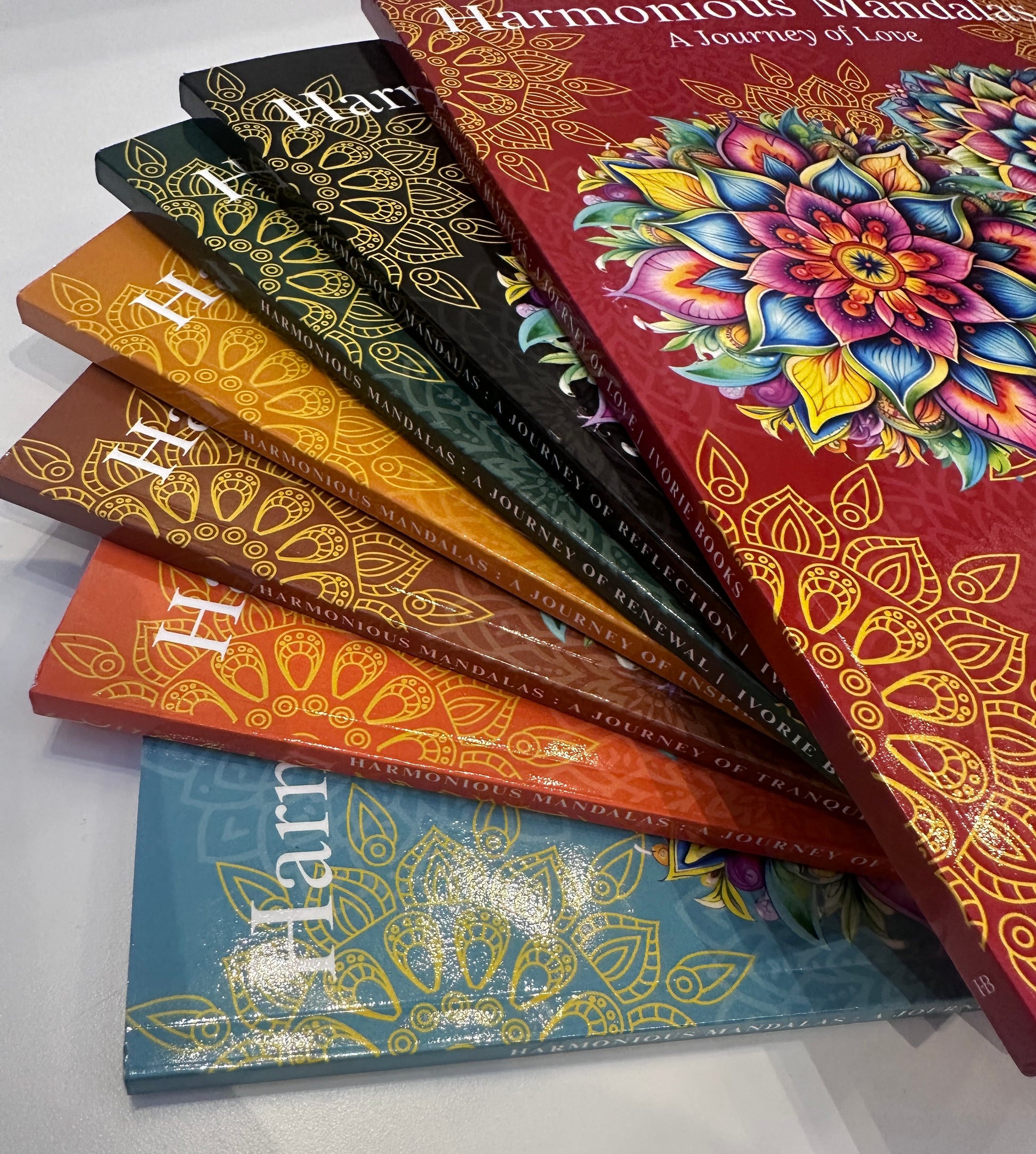 Angled view of Harmonious Mandalas paperback coloring books.
Angled view of the Harmonious Mandalas paperback collection, highlighting the colorful covers, book spines, and physical print finish.